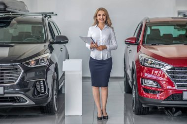 Araba galerisinde evrakları olan gülümseyen kadın.