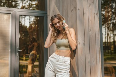 Akıllı telefondan iletişim kuran kadın saçına dokunuyor.