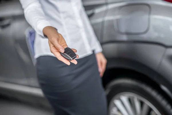 Vrouwen hand uit het houden van de sleutel tot nieuwe auto — Stockfoto