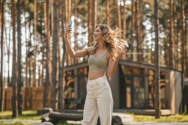 Çekici, mutlu bir kadın doğada selfie çekiyor.