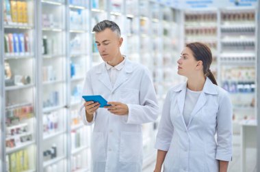 Tabletli beyaz önlüklü adam ve kadın meslektaşı.