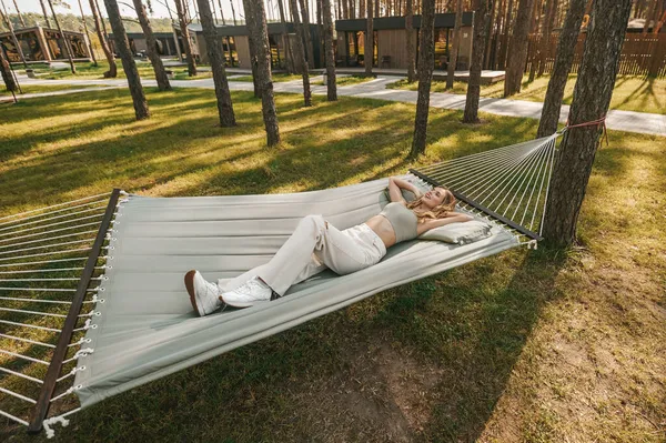 Jovem mulher calma deitada na rede ao ar livre — Fotografia de Stock