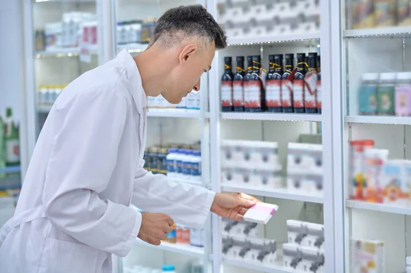 Konzentrierter Mann im Laborkittel überprüft Medikamente in Apotheke — Stockfoto