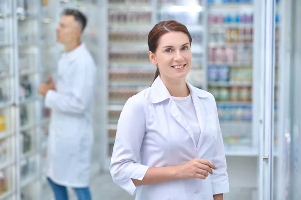 Lächelnde Frau und ernsthafter Mann in der Apotheke — Stockfoto