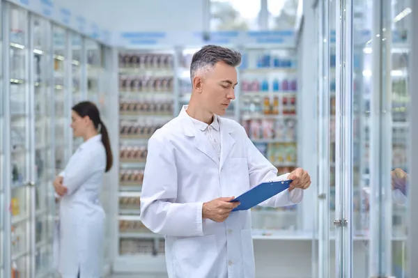 Homem de casaco branco com pasta na farmácia — Fotografia de Stock