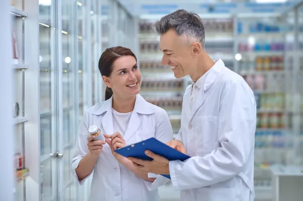 Женщина с лекарством и мужчина с папкой в аптеке — стоковое фото