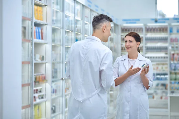 Два фармацевта обсуждают лекарства в аптеке — стоковое фото