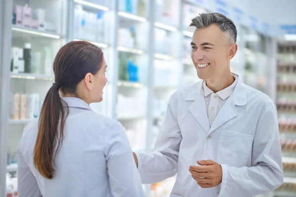 Два работника аптеки счастливо общаются на работе — стоковое фото