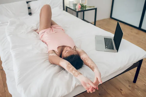 Une jeune femme couchée sur le lit, ordinateur portable à côté d'elle — Photo