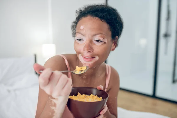 Una donna seduta sul letto e che fa colazione — Foto Stock