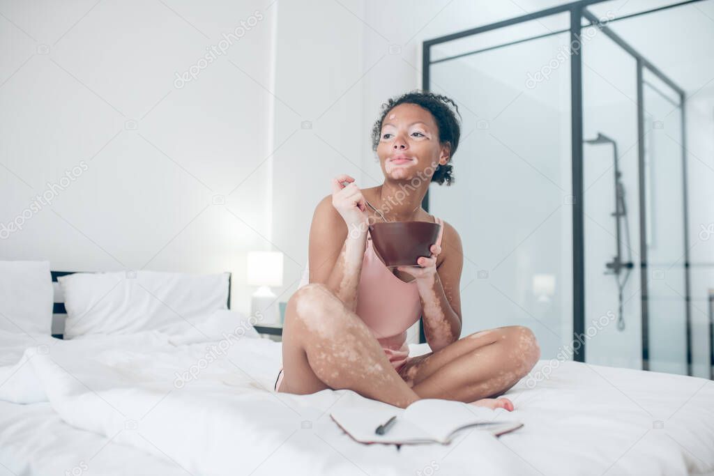 A woman sitting on bed and having breakfast