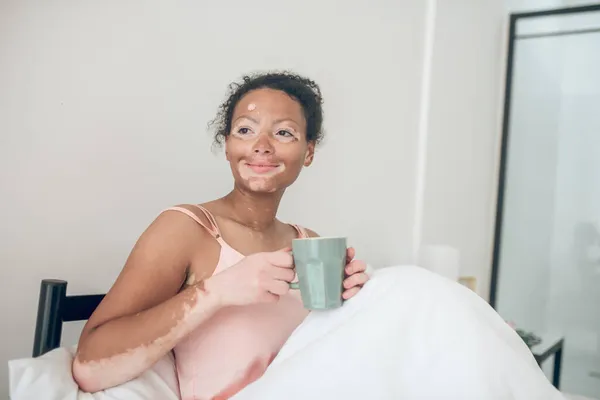 Μια γυναίκα που πίνει καφέ το πρωί ξαπλωμένη στο κρεβάτι — Φωτογραφία Αρχείου
