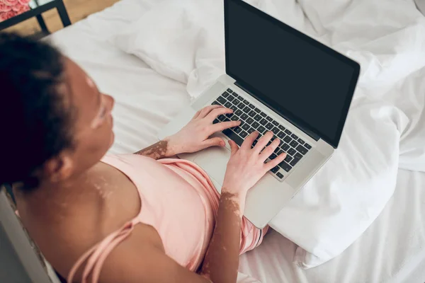 Μια γυναίκα που κάθεται στο κρεβάτι και εργάζεται σε ένα φορητό υπολογιστή — Φωτογραφία Αρχείου
