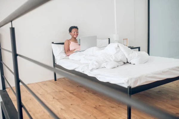 Nuori nainen, jolla on kannettava tietokone sängyssä kotona — kuvapankkivalokuva