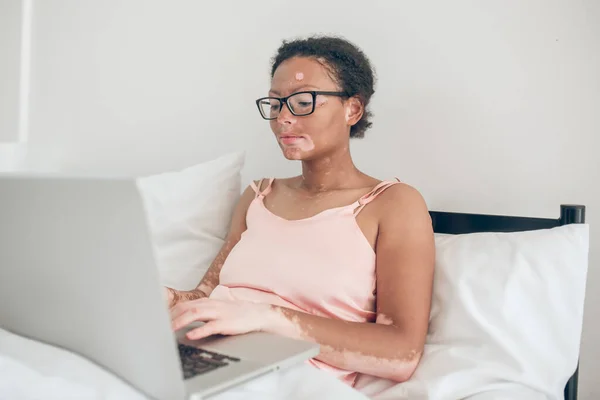 En mörkhyad kvinna skriva på laptop medan du sover — Stockfoto
