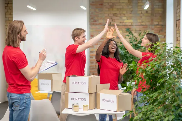 Молоді добровольці в червоних футболках на роботі в точці розповсюдження — стокове фото