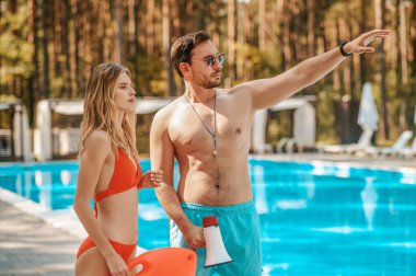 Erkek cankurtaran bayan iş arkadaşına bir şey gösteriyor.