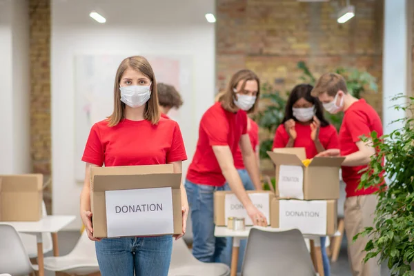 Dobrovolníci v obličejových maskách pracují s tříděním darů — Stock fotografie