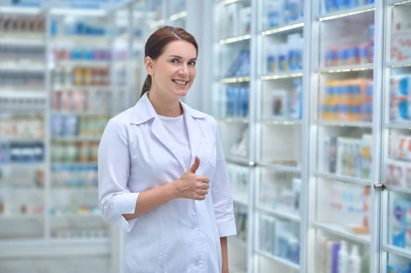 Glückliche Frau im weißen Mantel in der Apotheke — Stockfoto