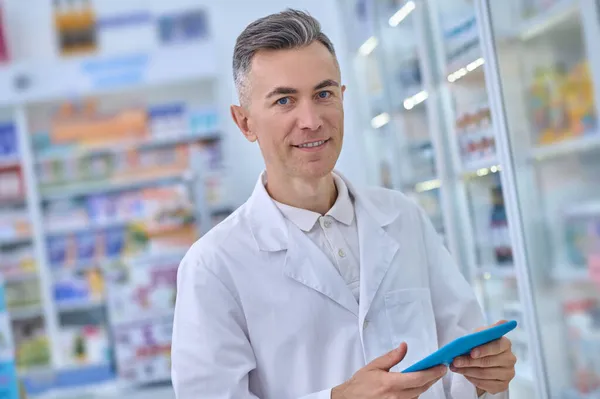 Lächeln im Arztkittel mit Tablette in der Apotheke — Stockfoto