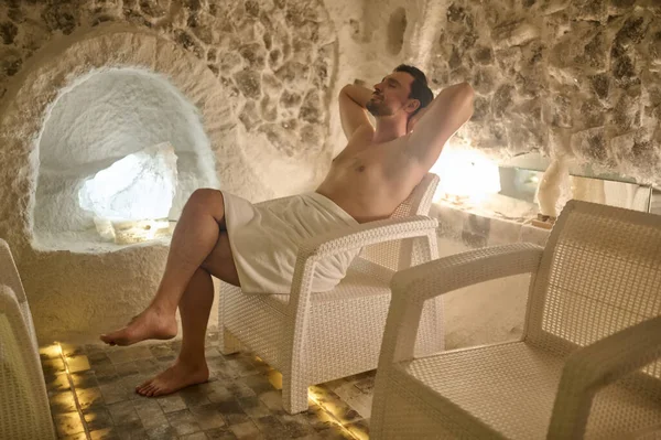 Ciemnowłosy mężczyzna wygląda na zrelaksowanego i cieszył się spędzając czas w centrum spa — Zdjęcie stockowe