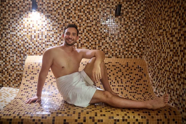Un hombre en una toalla sentado en la sauna y teniendo sesión de desintoxicación —  Fotos de Stock