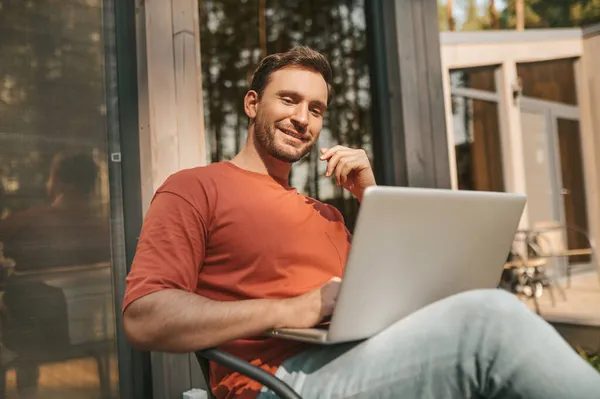 Vrolijke man zit met laptop buiten — Stockfoto