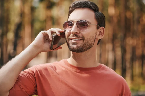 Kulağında akıllı telefon olan güneş gözlüklü bir adam. — Stok fotoğraf