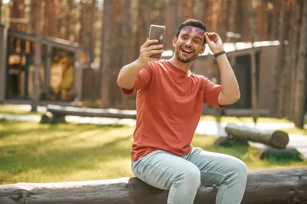 Mutlu adam uzanmış elinde akıllı telefona bakıyor. — Stok fotoğraf