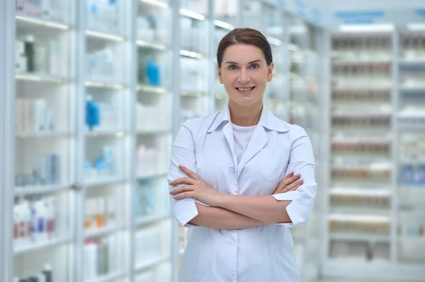 Mujer sonriente en bata blanca en farmacia — Foto de Stock