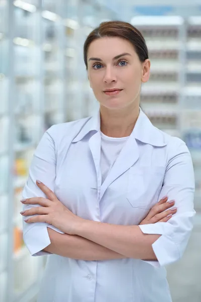 Confident woman in lab coat in pharmacy hall — Stock Photo, Image