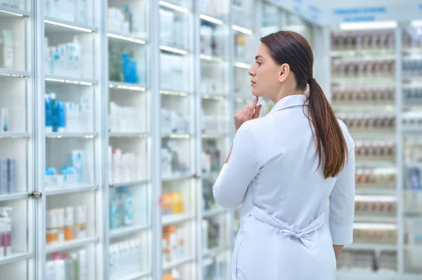 Vista posterior de la mujer en bata blanca en la farmacia —  Fotos de Stock