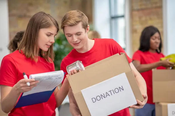 Volontärer i röda thsirt deltar om donationer delas ut — Stockfoto