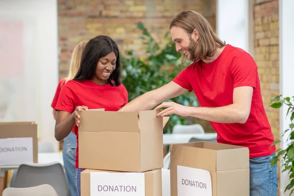 Voluntarios en rojo thsirts tomando parte si la distribución de donaciones — Foto de Stock