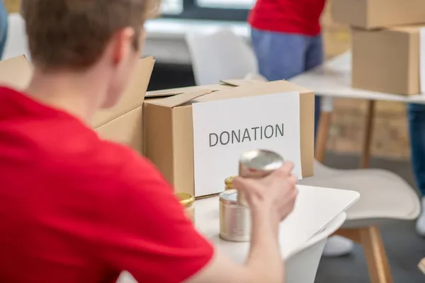 Volontärer i röda thsirt deltar om donationer delas ut — Stockfoto