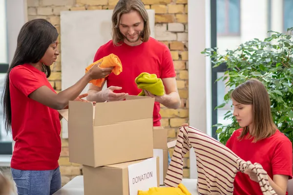 Dobrovolníci v červených tričkách se účastní v případě rozdělení darů — Stock fotografie