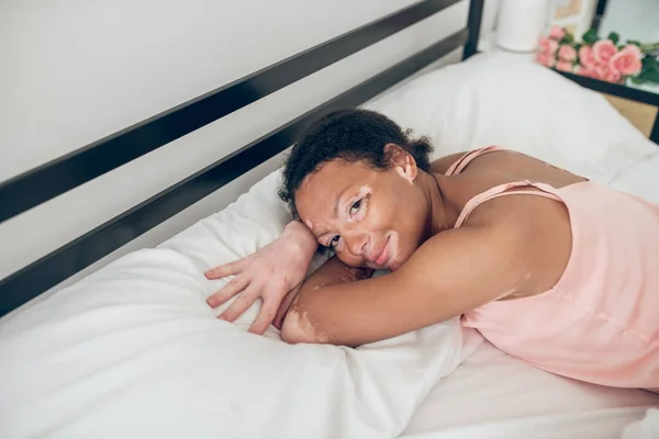 Uma jovem deitada na cama e olhando relaxada — Fotografia de Stock