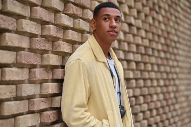 Koyu tenli, bej ceketli genç bir adamın vesikalığı.