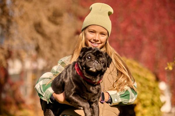 Hübsches blondes Mädchen hält ihren Hund und lächelt — Stockfoto