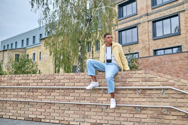 Ung manlig fotograf sitter på tegelväggen — Stockfoto