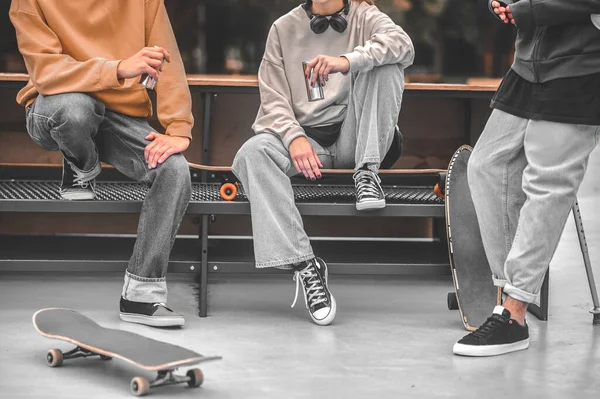 Three skateboarders with skateboards communicating near bench — Stock Photo, Image