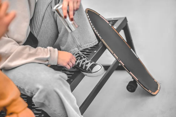 Πόδια κοντά skateboard του ατόμου που κάθεται στον πάγκο πάρκο — Φωτογραφία Αρχείου