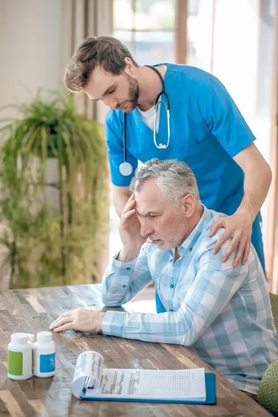 Doctor atento apoyando a un hombre deprimido de pelo gris — Foto de Stock