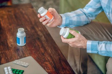 Ahşap bir masada oturan erkek beslenme takviyesi seçiyor.