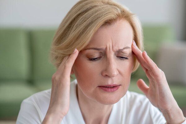 Женщина среднего возраста, страдающая головной болью