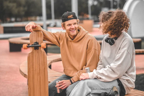 Κορίτσι και τύπος με skateboards μιλάμε κάθεται στον πάγκο — Φωτογραφία Αρχείου