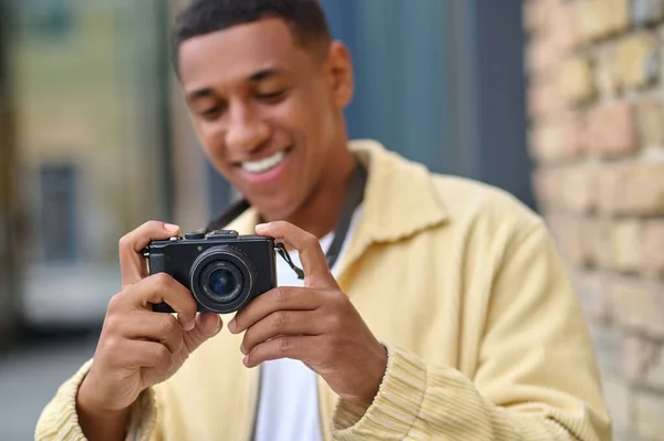 Elinde kamera olan pozitif fotoğrafçı mutlu görünüyor. — Stok fotoğraf