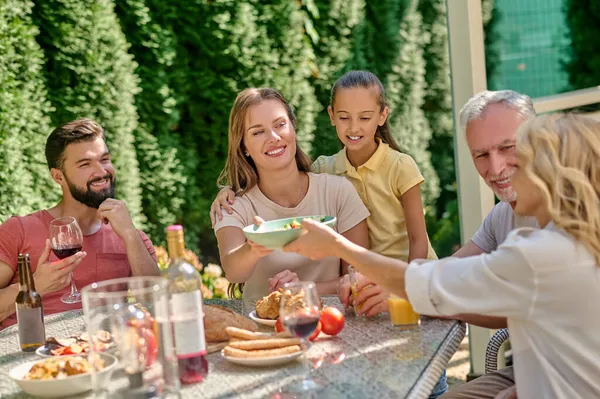 Uma família sentada à mesa de jantar e alegre — Fotografia de Stock