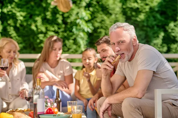 Una familia sentada en la mesa y con un aspecto alegre — Foto de Stock