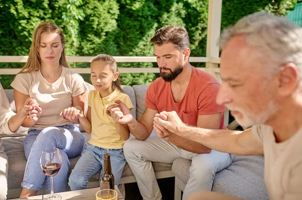 Egy család, akik csukott szemmel imádkoznak vacsora előtt. — Stock Fotó